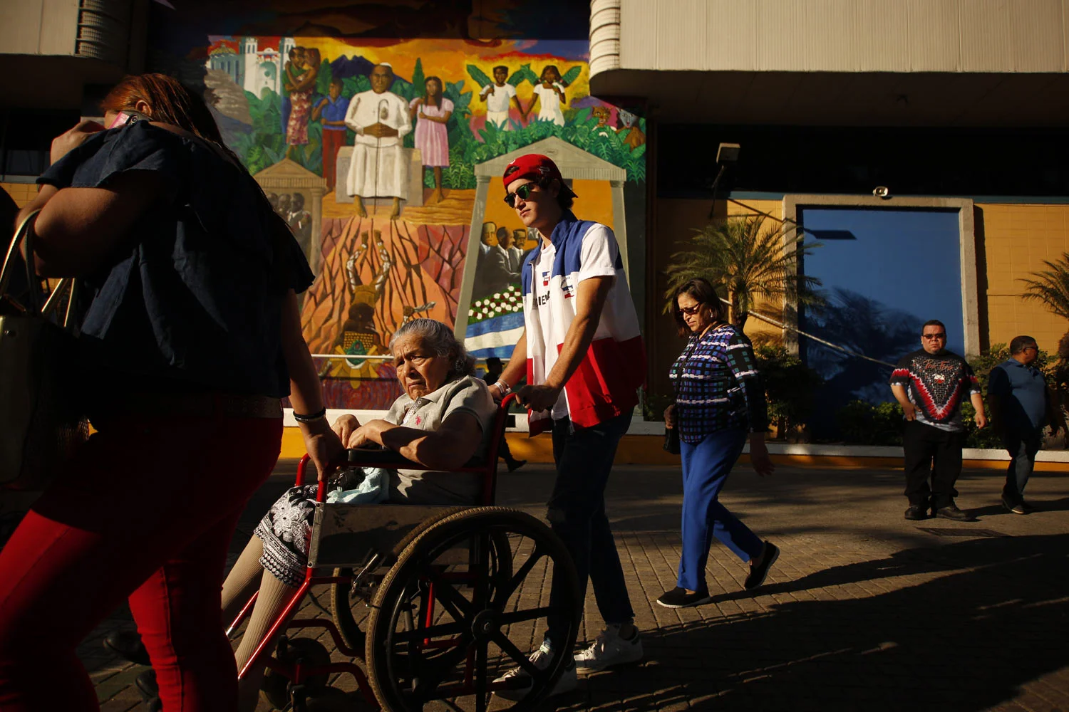 An election volunteer helps a woman in a wheelchair reach her voting table during the presidential election in San Salvador, El Salvador, Sunday, Feb. 3, 2019. Voters are choosing from among a handful of presidential candidates all promising to end corruption, stamp out gang violence and create more jobs in the Central American nation. (AP Photo/Salvador Melendez)