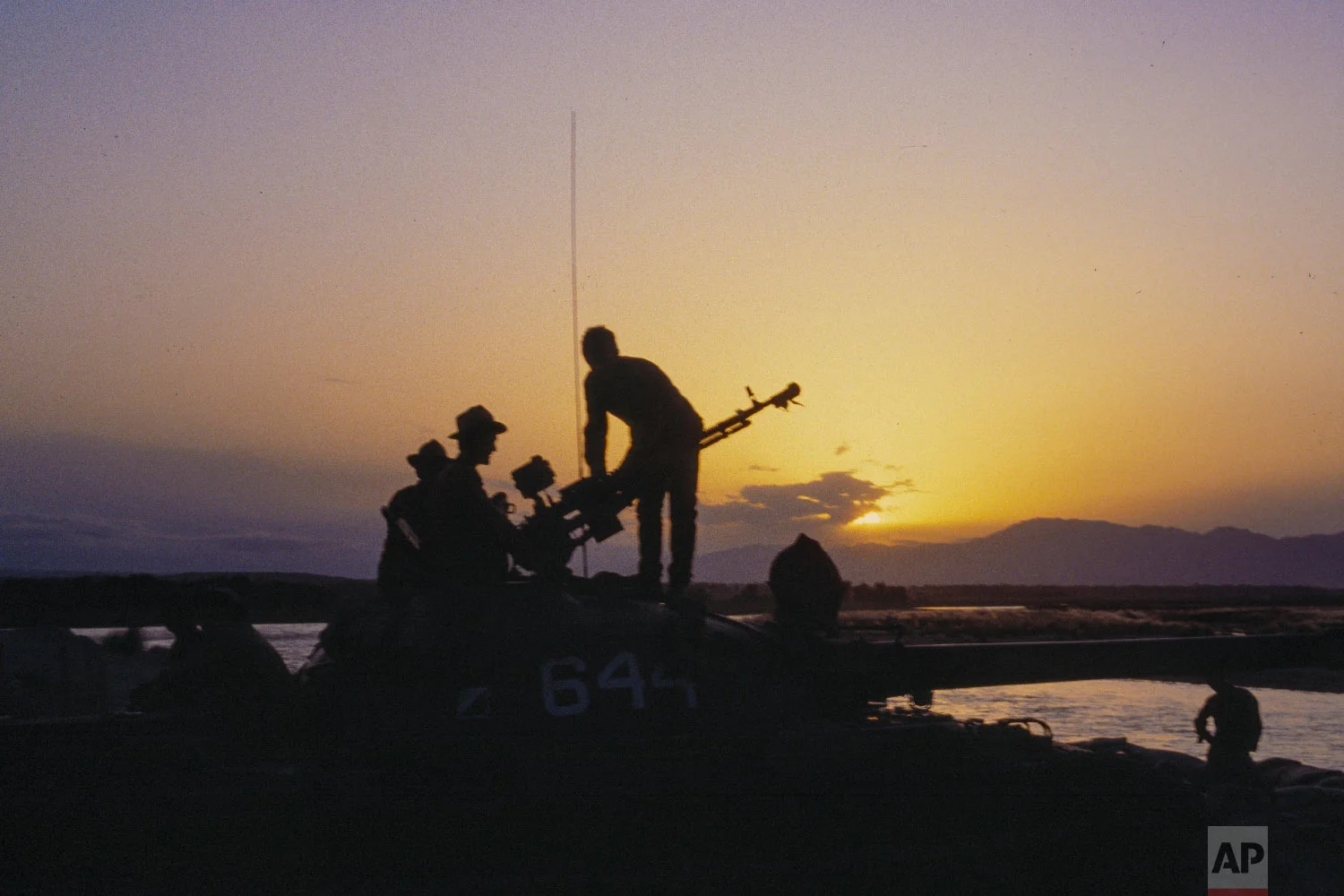 Soviet Army soldiers stand atop of a tank at a outpost during sunset in Afghanistan on September 1984. (AP Photo/Alexander Zemlianichenko)