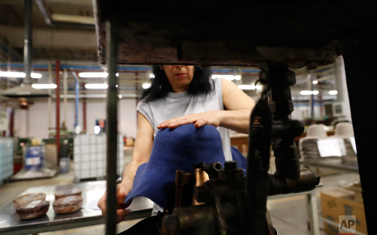 A woman moulds a hat inside Borsalino's hat factory, in Spinetta Marengo, near Alessandria, Italy, Thursday, Jan. 17, 2019. (AP Photo/Antonio Calanni)