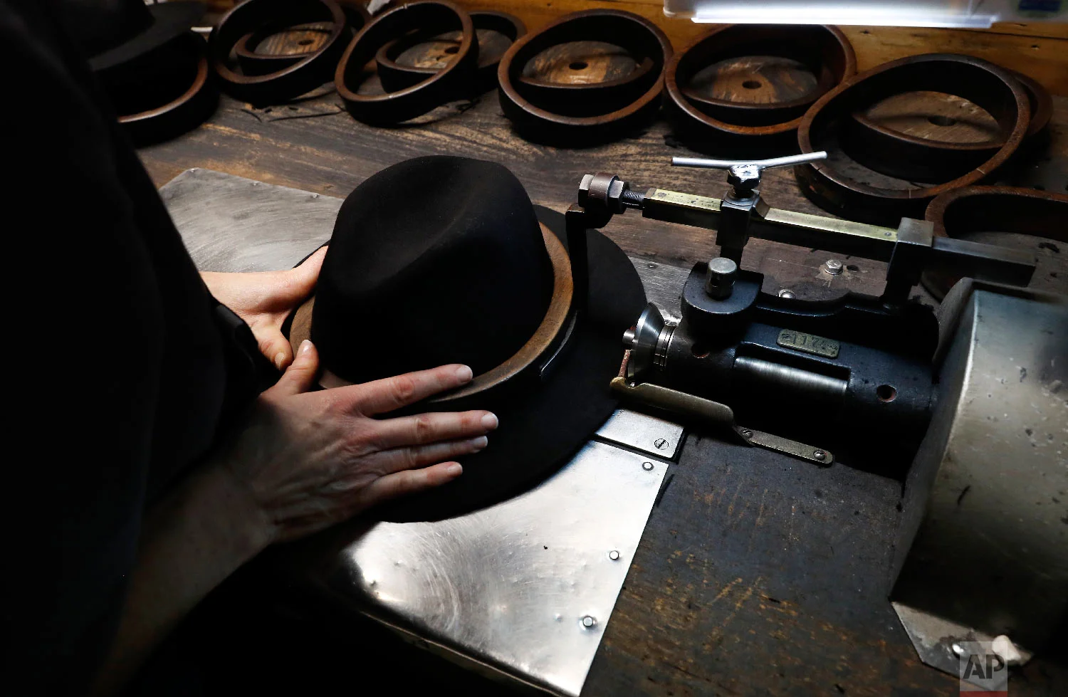 A man holds a hat inside the Borsalino hat factory, in Spinetta Marengo, near Alessandria, Italy, Thursday, Jan. 17, 2019. (AP Photo/Antonio Calanni)