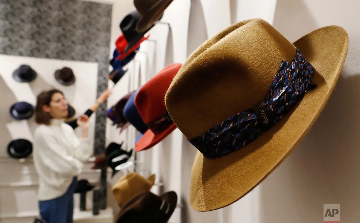 A woman looks at hats in a Borsalino store in downtown Milan, Italy, Wednesday, Jan. 16, 2019. (AP Photo/Antonio Calanni)