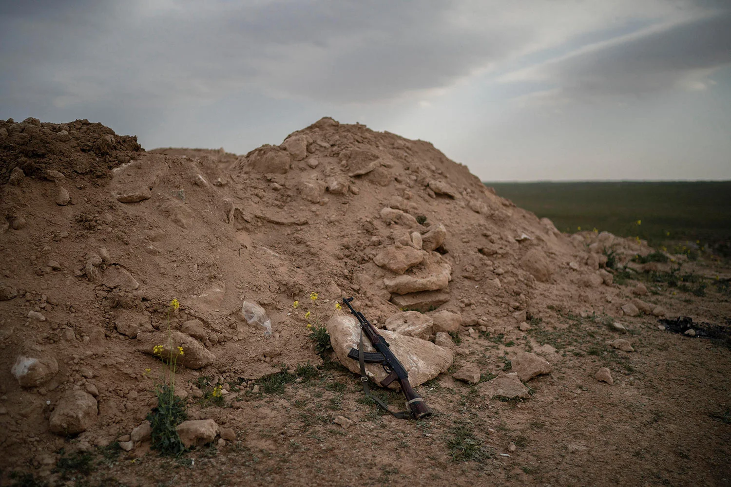 An AK-47 rifle, belonging to a U.S.-backed Syrian Democratic Forces (SDF) fighter, rests on a rock on a hill in the desert outside the village of Baghouz, Syria, Thursday, Feb. 14, 2019. U.S.-backed Syrian forces are clearing two villages in eastern Syria of remaining Islamic State militants who are hiding among the local population, and detaining others attempting to flee with the civilians, the U.S.-led coalition said Thursday. (AP Photo/Felipe Dana)