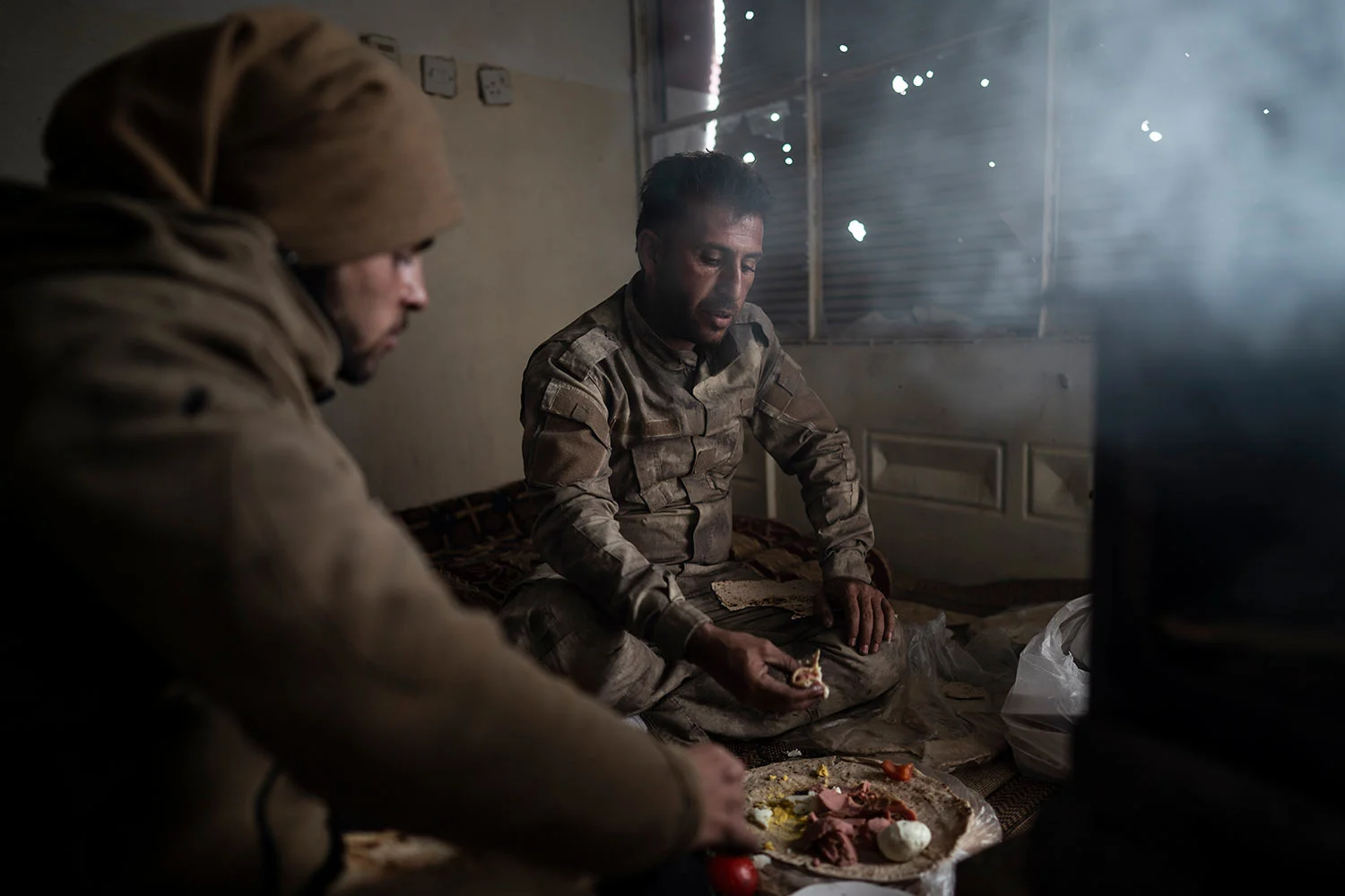 U.S.-backed Syrian Democratic Forces (SDF) fighters eat in a building as the fight against Islamic State militants continues in the village of Baghouz, Syria, Sunday, Feb. 17, 2019. Islamic State militants are preventing more than 1,000 civilians from leaving a tiny area still held by the extremist group in a village in eastern Syria, a spokesman for the U.S.-backed Syrian militia fighting the group said Sunday. (AP Photo/Felipe Dana)