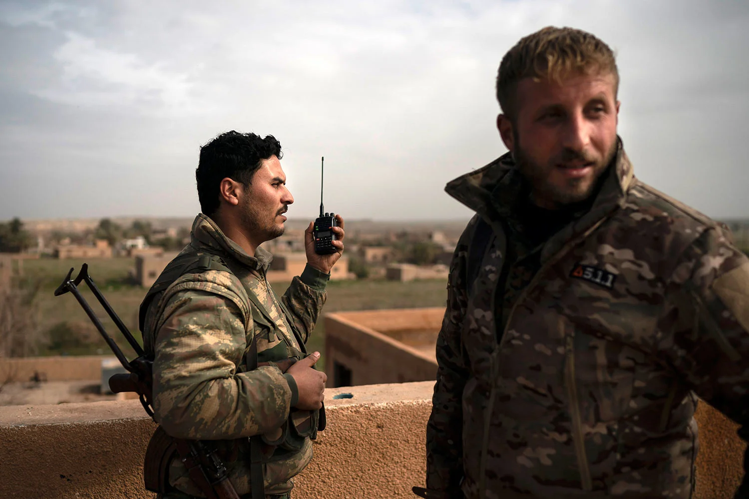 U.S.-backed Syrian Democratic Forces (SDF) fighters talk on a radio in a rooftop position as fight against Islamic State militants continues in the village of Baghouz, Syria, Saturday, Feb. 16, 2019. (AP Photo/Felipe Dana)