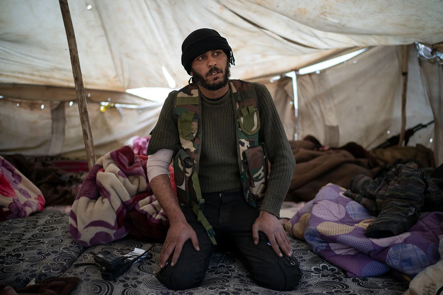 A U.S.-backed Syrian Democratic Forces (SDF) fighter sits inside a tent atop a hill in the desert outside the village of Baghouz, Syria, Thursday, Feb. 14, 2019. (AP Photo/Felipe Dana)