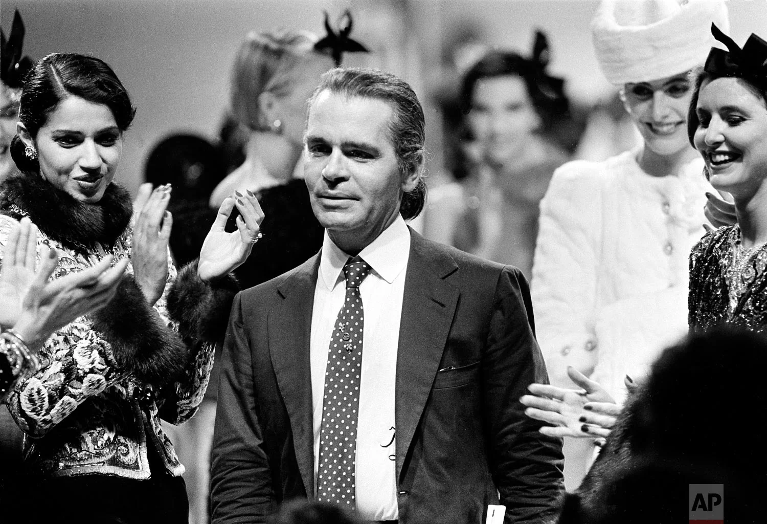 German fashion designer Karl Lagerfeld is applauded by his models at the end of the presentation of Chanel's fall and winter haute couture collection in Paris, France, July 26, 1983. (AP Photo/Jacques Langevin)