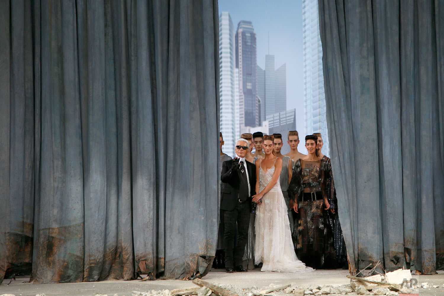 German fashion designer Karl Lagerfeld, foreground left, stands with models on stage as he acknowledges applause following the presentation of the Haute Couture Fall-Winter 2013-2014 collection he designed for Chanel, July 2, 2013 in Paris. (AP Photo/Francois Mori)