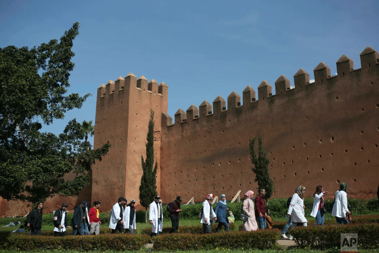 Protesting teachers walk past ancient walls in Rabat, Morocco, Feb. 20, 2019. (AP Photo/Mosa'ab Elshamy)