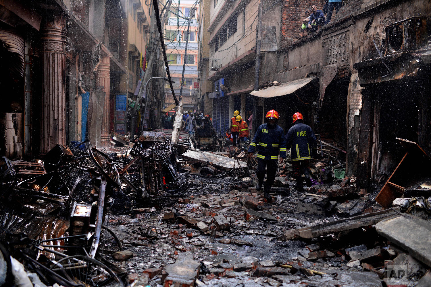 Firefighters gather around buildings that caught fire late Wednesday night in Dhaka, Bangladesh, Thursday, Feb. 21, 2019. (AP Photo/Mahmud Hossain Opu)