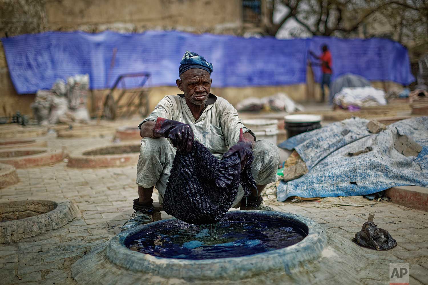 In this photo taken Tuesday, Feb. 19, 2019, a craftsman dyes cloth with indigo in one of the ancient dye pits of Kofar Mata in Kano, northern Nigeria. (AP Photo/Ben Curtis) 