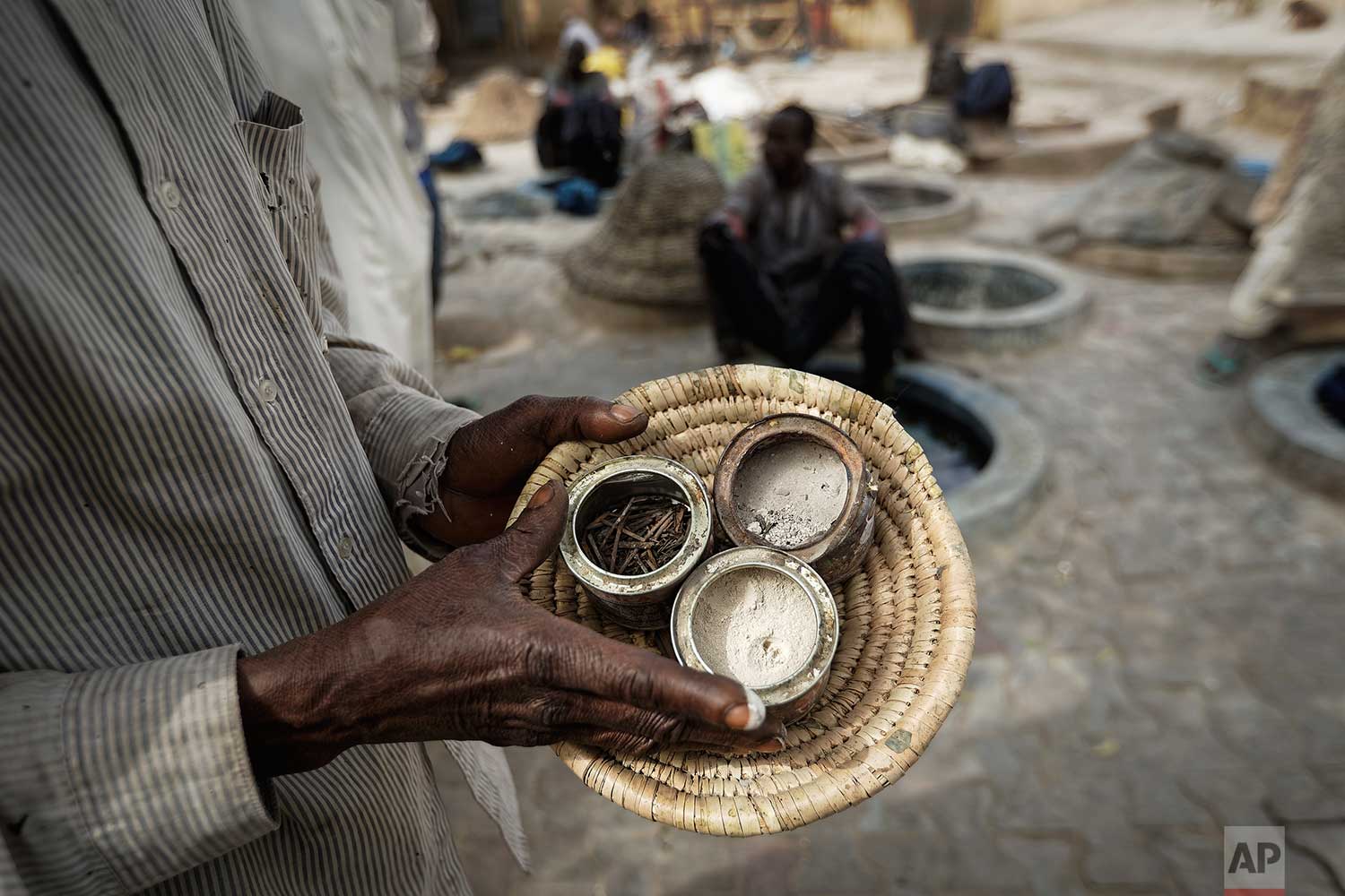  In this photo taken Tuesday, Feb. 19, 2019, a craftsman carries some of the ingredients used to make indigo dye, at the ancient dye pits of Kofar Mata in Kano, northern Nigeria. (AP Photo/Ben Curtis) 