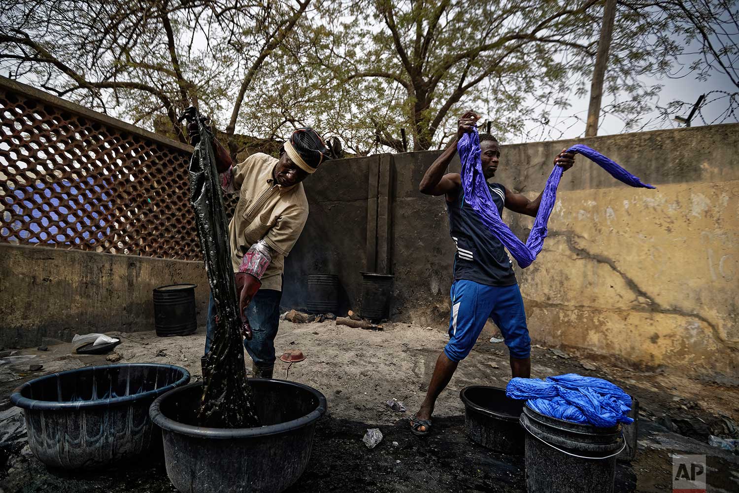  In this photo taken Tuesday, Feb. 19, 2019, craftsmen dye cloths in buckets next to the ancient dye pits of Kofar Mata in Kano, northern Nigeria. (AP Photo/Ben Curtis) 
