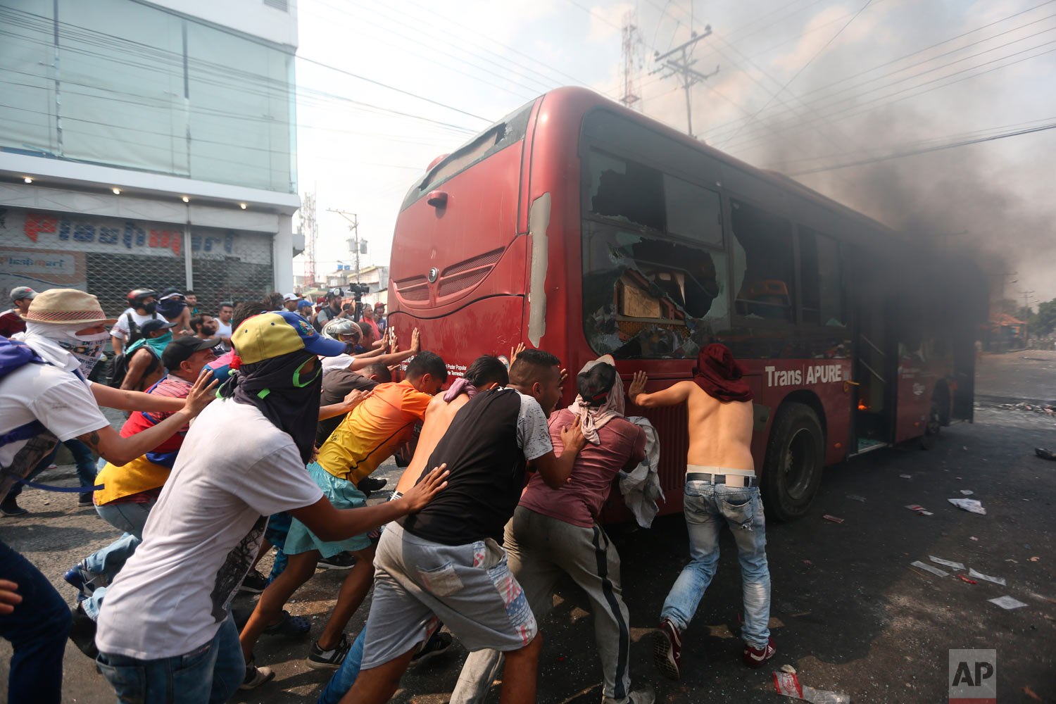  Demonstrators push away a bus that was torched during clashes with the Venezuelan Bolivarian National Guard in Urena, Venezuela, near the border with Colombia, Saturday, Feb. 23, 2019. (AP Photo/Fernando Llano) 