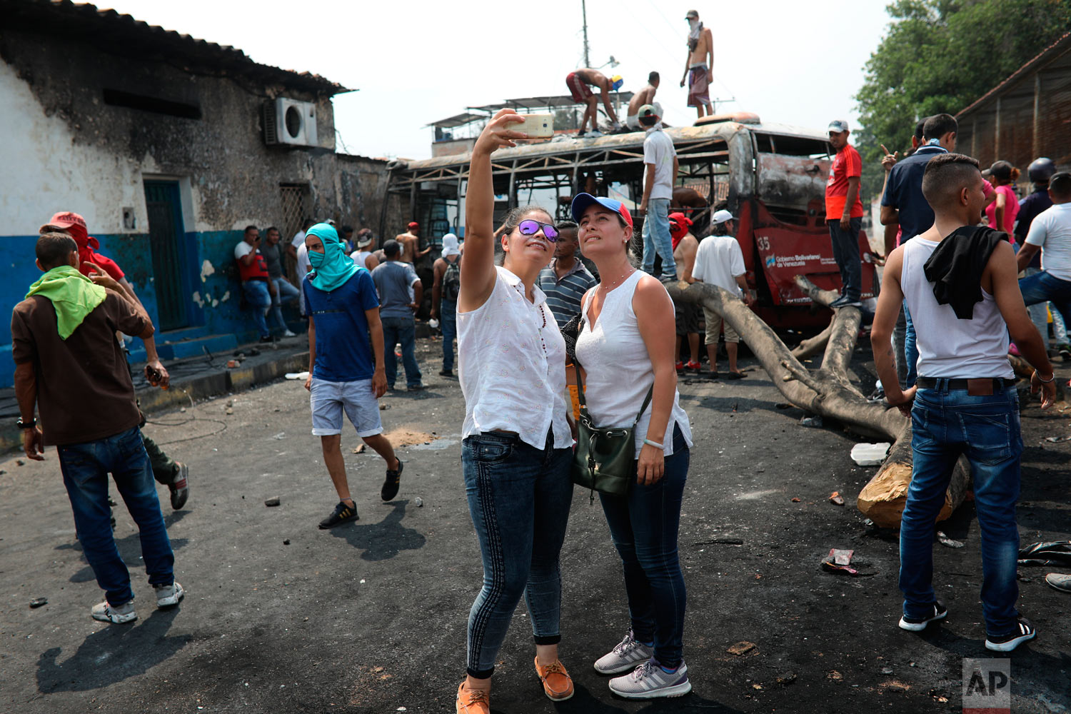  Opposition demonstrators take a selfie at the site where a torched bus is used as a barricade, during clashes with the Venezuelan Bolivarian National Guard in Urena, Venezuela, near the border with Colombia, Saturday, Feb. 23, 2019. (AP Photo/Rodrig