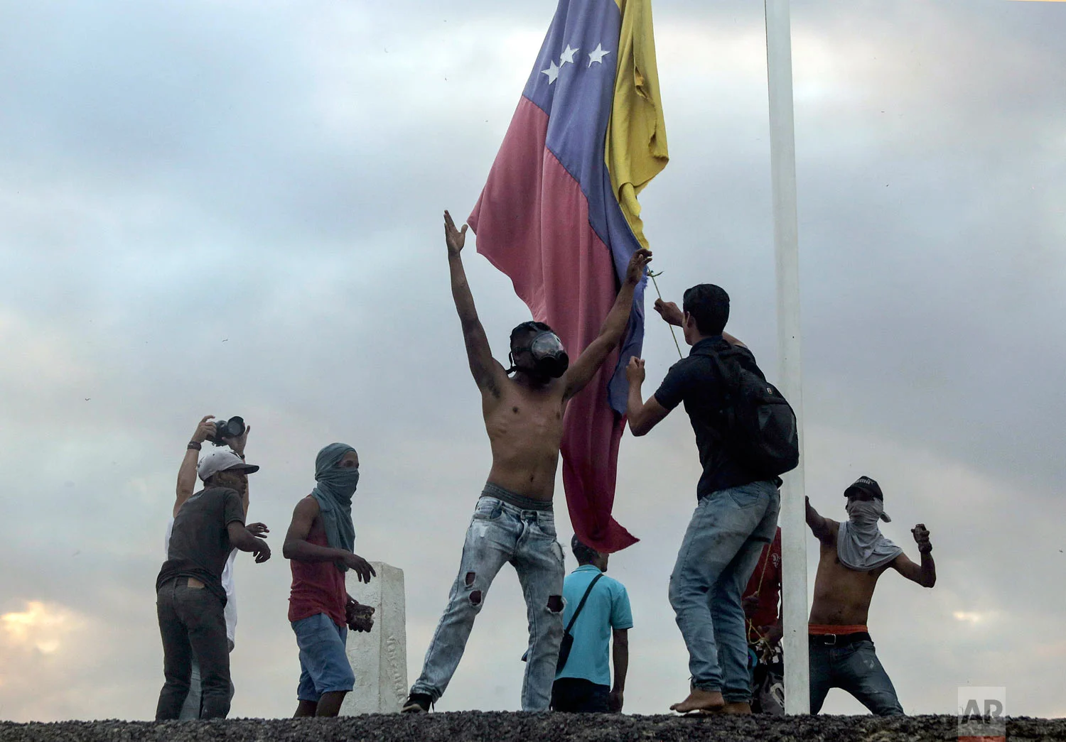 Protestors bring down the Venezuelan national flag at the border between Brazil and Venezuela, in Pacaraima, Roraima state, Brazil, Saturday, Feb. 23, 2019. (AP Photo/Ivan Valencia)