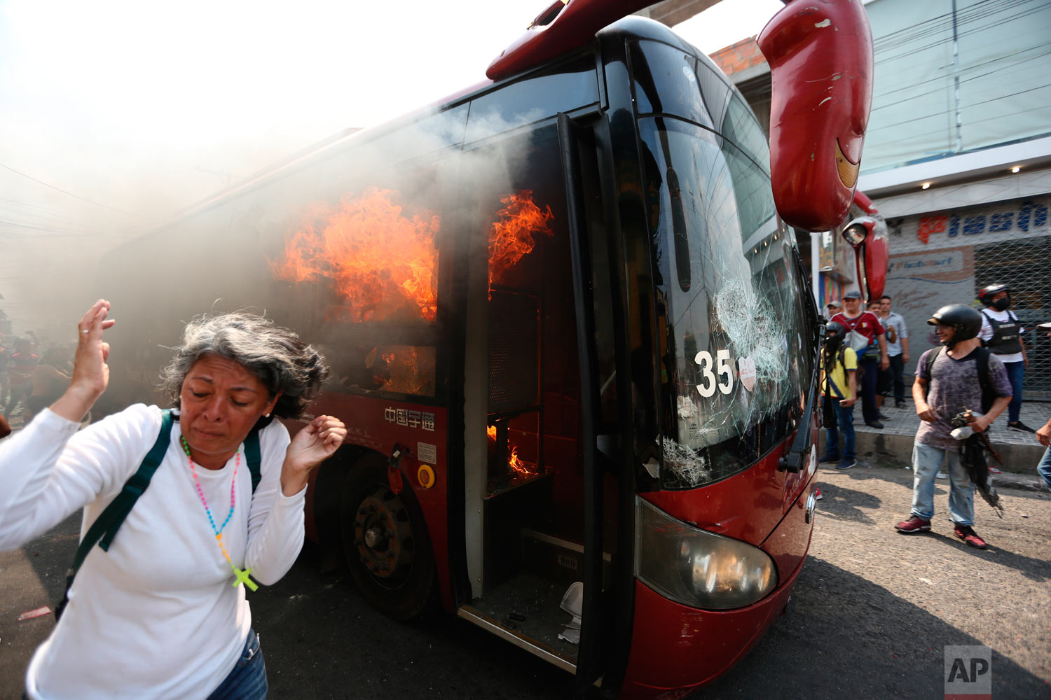  A woman moves away from the flames of a burning bus after it was pushed away during clashes with the Venezuelan Bolivarian National Guard in Urena, Venezuela, near the border with Colombia, Saturday, Feb. 23, 2019. (AP Photo/Fernando Llano) 