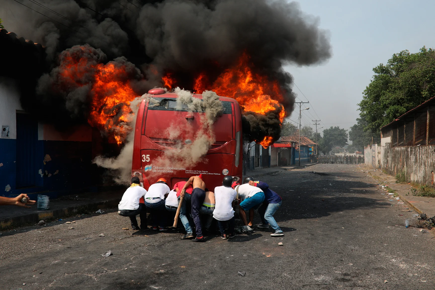Demonstrators push a bus that was torched during clashes with the Venezuelan Bolivarian National Guard in Urena, Venezuela, near the border with Colombia, Saturday, Feb. 23, 2019. (AP Photo/Rodrigo Abd)