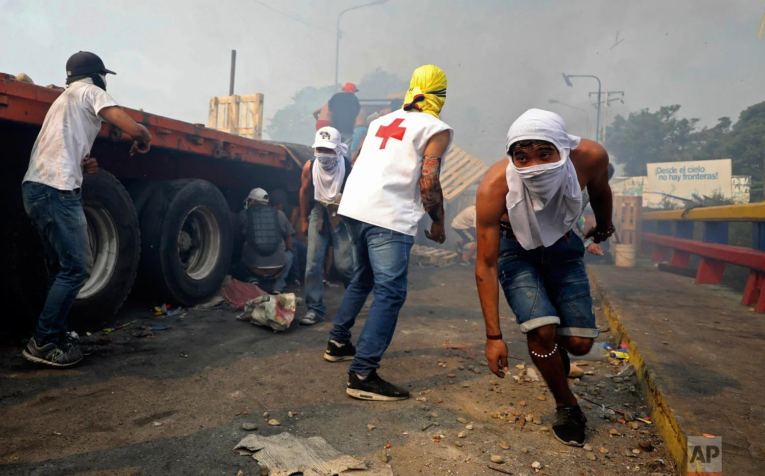 Venezuelan youth clash with Venezuelan National Guard next to a semi-trailer that was part of a humanitarian aid convoy that failed to cross the Francisco de Paula Santander international bridge in Cucuta, Colombia, Saturday, Feb. 23, 2019. (AP Photo/Fernando Vergara)