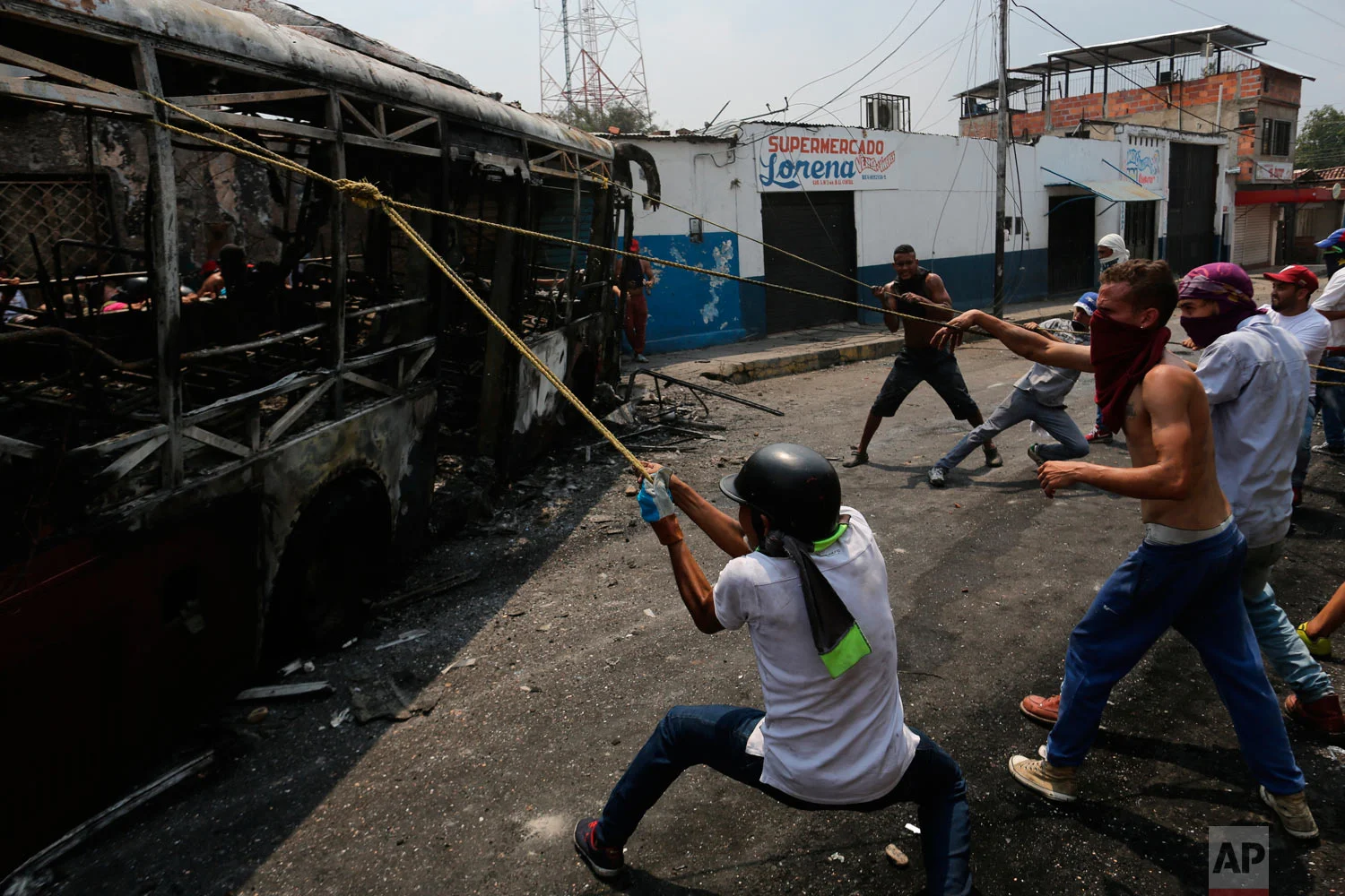 Demonstrators move a torched bus during clashes with the Venezuelan Bolivarian National Guard in Urena, Venezuela, near the border with Colombia, Saturday, Feb. 23, 2019. (AP Photo/Rodrigo Abd)