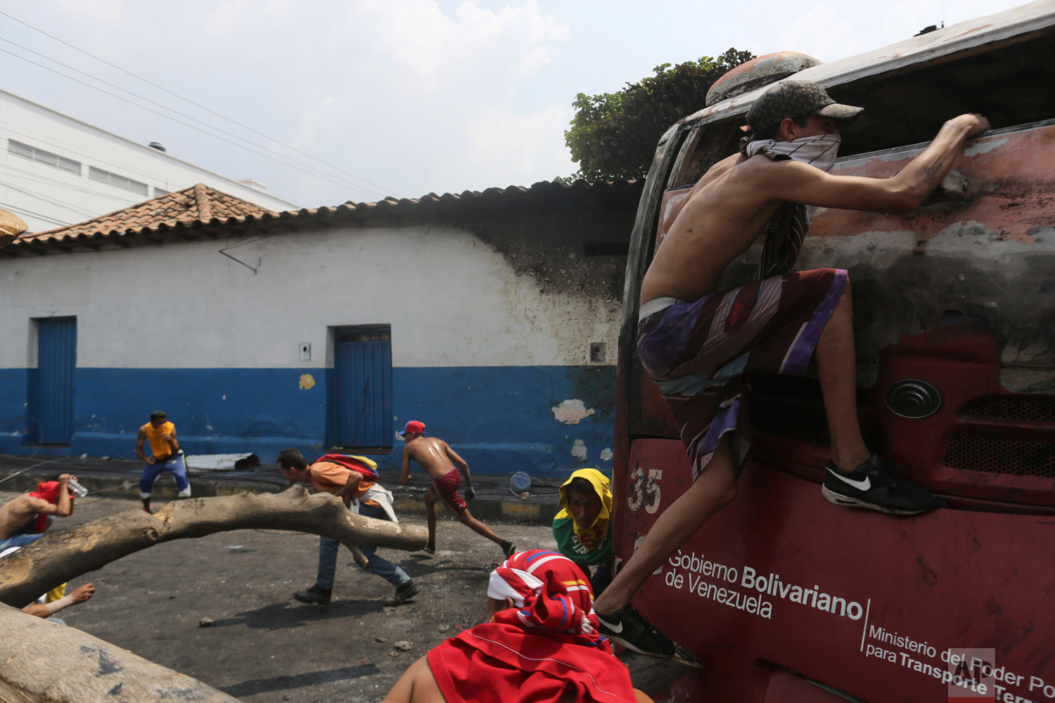  Demonstrators take cover behind a torched bus, during clashes with the Venezuelan Bolivarian National Guard in Urena, Venezuela, near the border with Colombia, Saturday, Feb. 23, 2019. (AP Photo/Rodrigo Abd) 