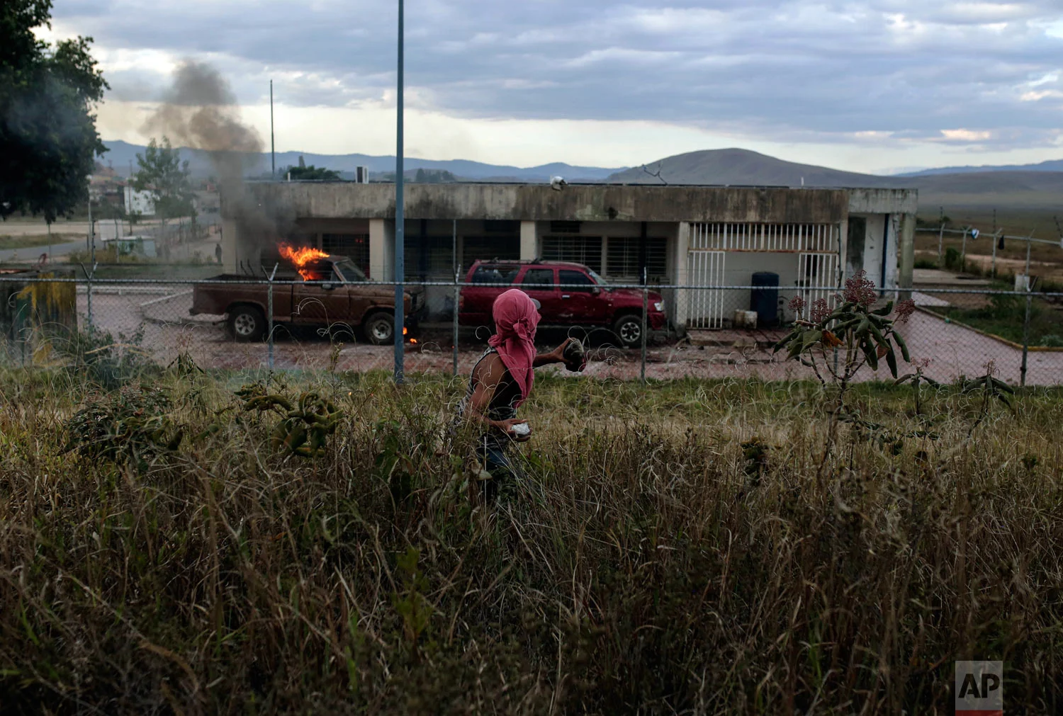 A demonstrator throws a stone at a Venezuelan military post at the border between Brazil and Venezuela, in Pacaraima, Roraima state, Brazil, Saturday, Feb.23, 2019. (AP Photo/Ivan Valencia)