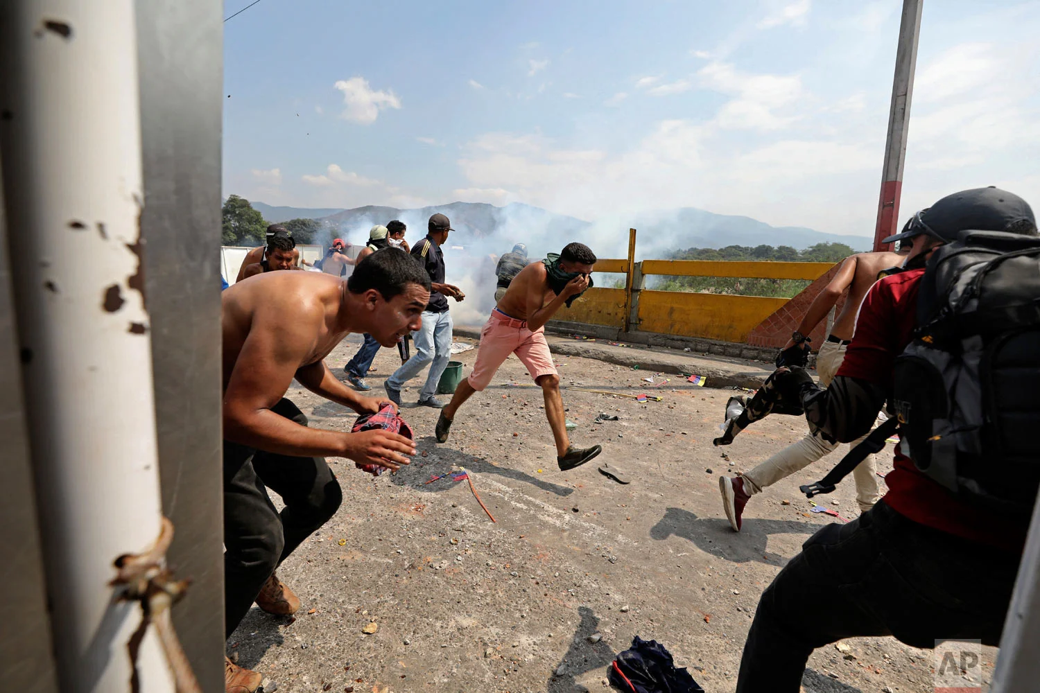 People run for cover from tear gas launched by Venezuela's National Guard as they try to clear the barricaded Simon Bolivar international bridge in Cucuta, Colombia, Saturday, Feb. 23, 2019. (AP Photo/Fernando Vergara)