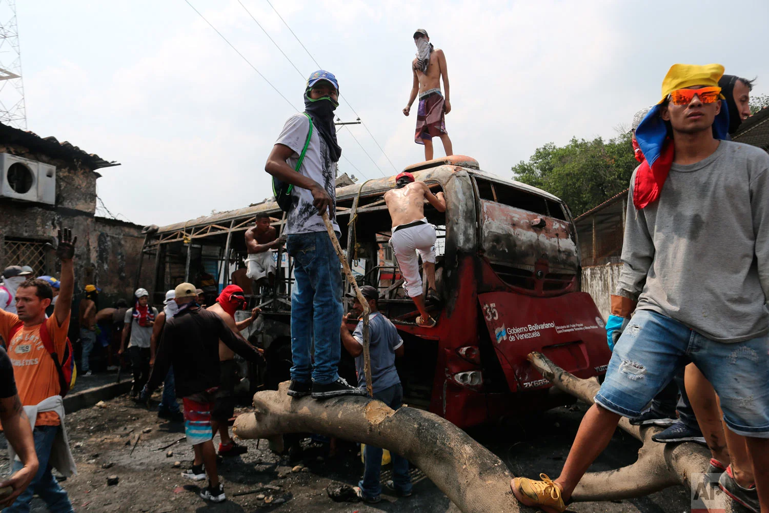 Demonstrators stand on a torched bus during clashes with the Venezuelan Bolivarian National Guard in Urena, Venezuela, near the border with Colombia, Saturday, Feb. 23, 2019. (AP Photo/Rodrigo Abd)