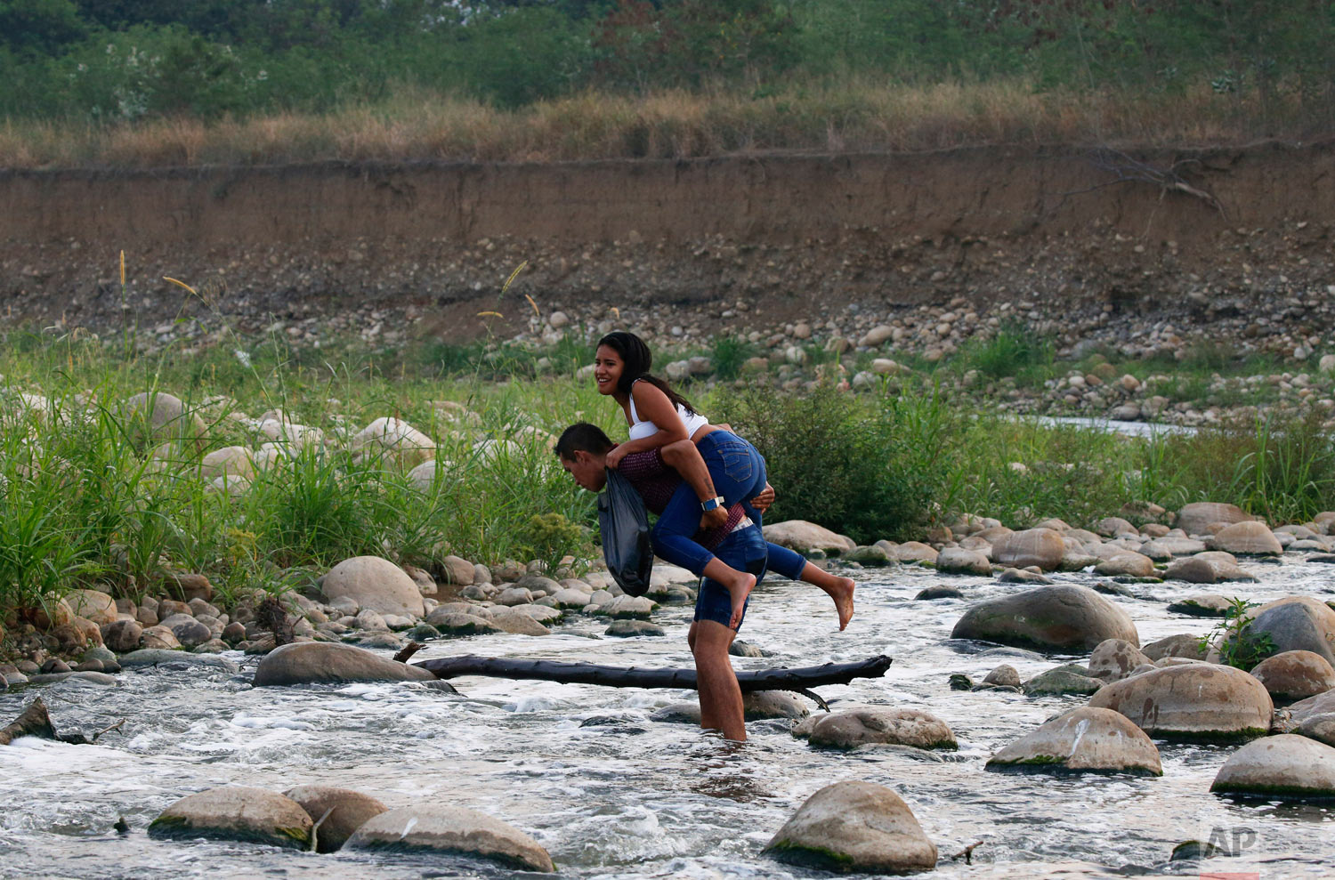 A young woman is carried across the Tachira River at the border between Venezuela and Colombia to attend the Venezuela Aid Live concert in Palotal, Venezuela, Friday, Feb. 22, 2019. (AP Photo/Fernando Llano)