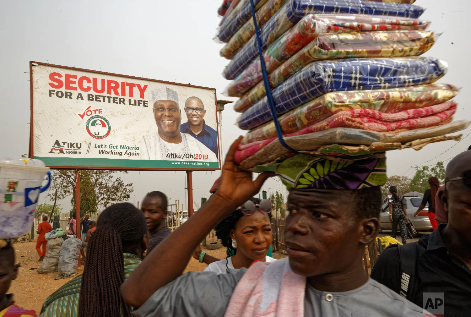 A street seller sells his wares by the side of the road next to a campaign poster for opposition presidential candidate Atiku Abubakar, at a busy intersection near Nyanya, on the eastern outskirts of the capital Abuja, Nigeria, Feb. 12, 2019. (AP Photo/Ben Curtis)