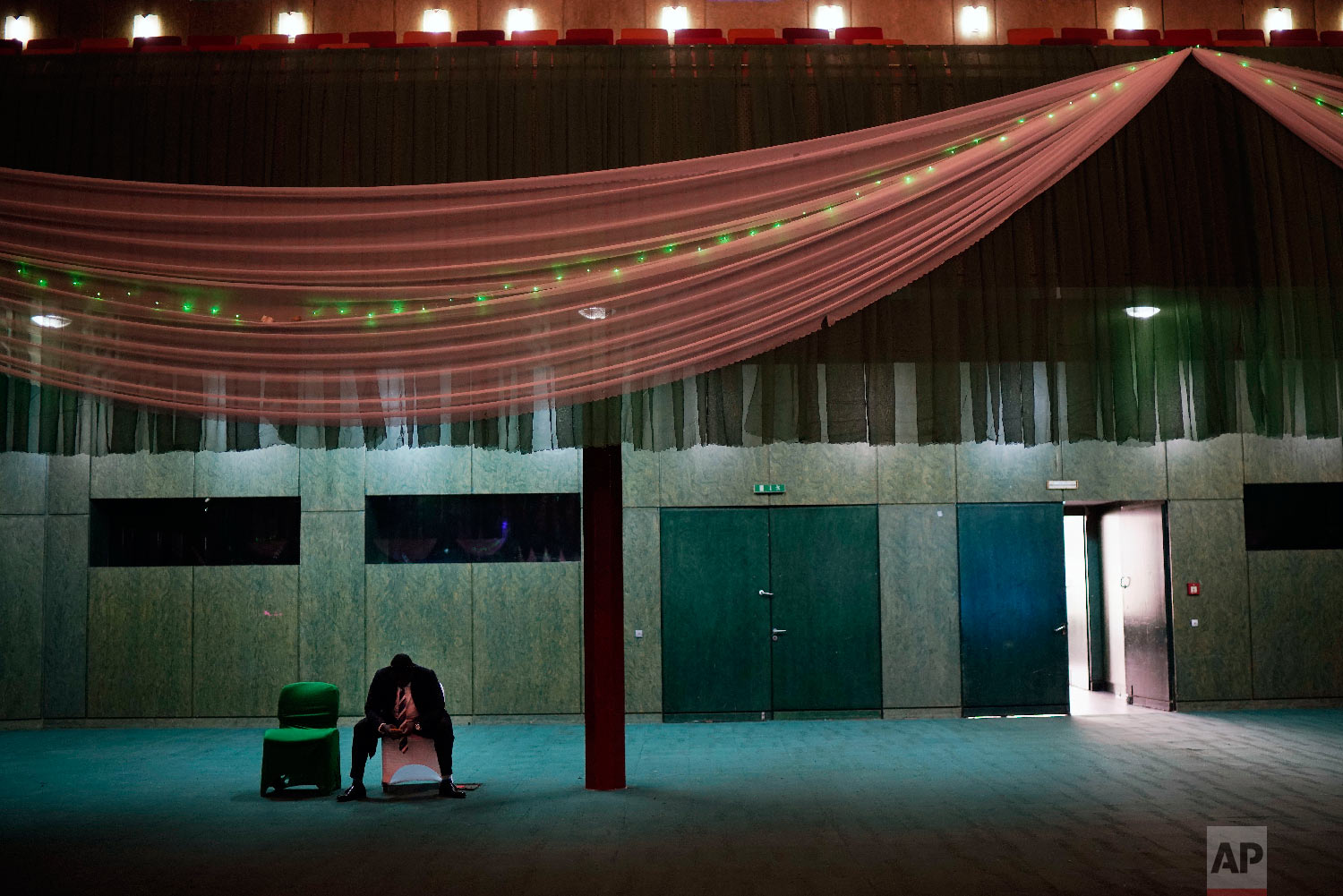 A man checks his phone at the International conference center in Abuja, Nigeria, Feb. 16, 2019 , where Nigeria's electoral commission chairman Mahmoud Yakubu arrives to meet with election stakeholders following the sudden postponement of the presidential election until Feb. 23. (AP Photo/Jerome Delay)