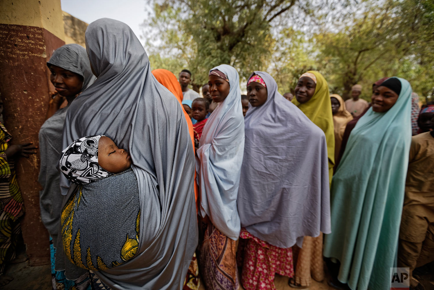 A baby sleeps on his mother's back as women queue in line to cast their votes in the village of Tumfafi, near Kano, in northern Nigeria, Feb. 23, 2019. (AP Photo/Ben Curtis)