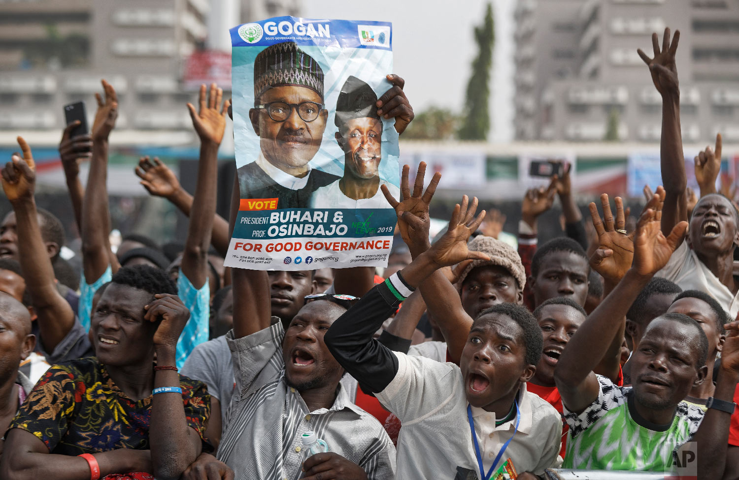 Supporters of incumbent President Muhammadu Buhari, holding a poster of Buhari and and Vice President Yemi Osinbajo, cheer as he arrives at a campaign rally in Abuja, Nigeria, Feb. 13, 2019. (AP Photo/Ben Curtis)