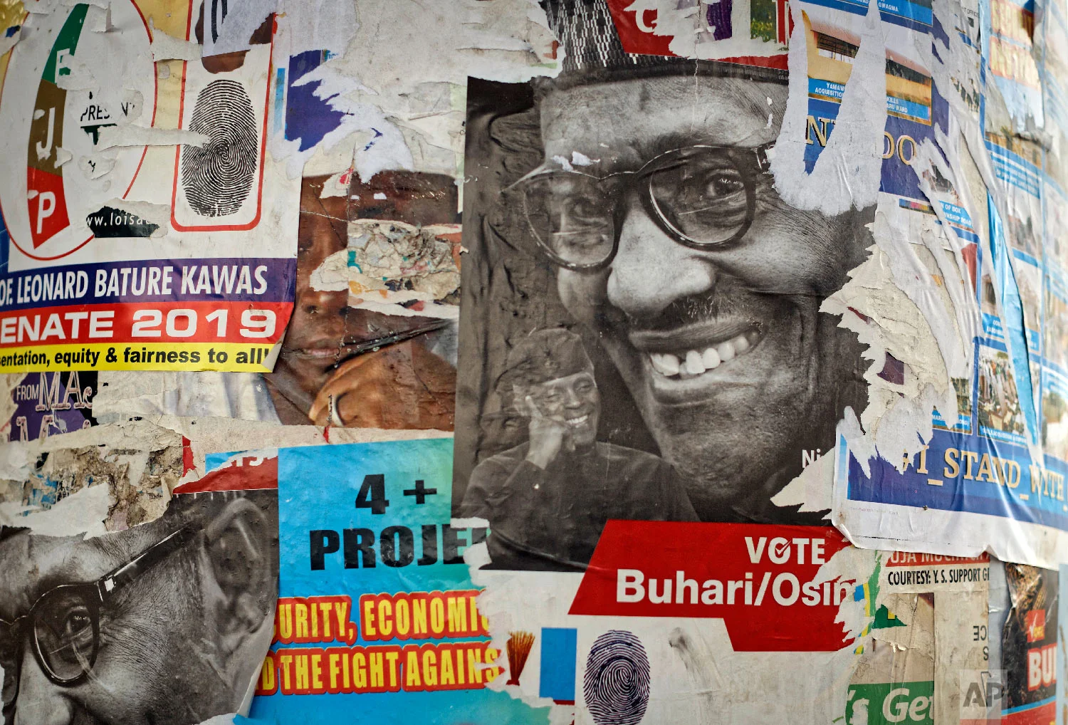 The faces of incumbent President Muhammadu Buhari and Vice President Yemi Osinbajo are seen on partially-ripped campaign posters near Nyanya, on the eastern outskirts of the capital Abuja, Nigeria, Feb. 12, 2019. (AP Photo/Ben Curtis)