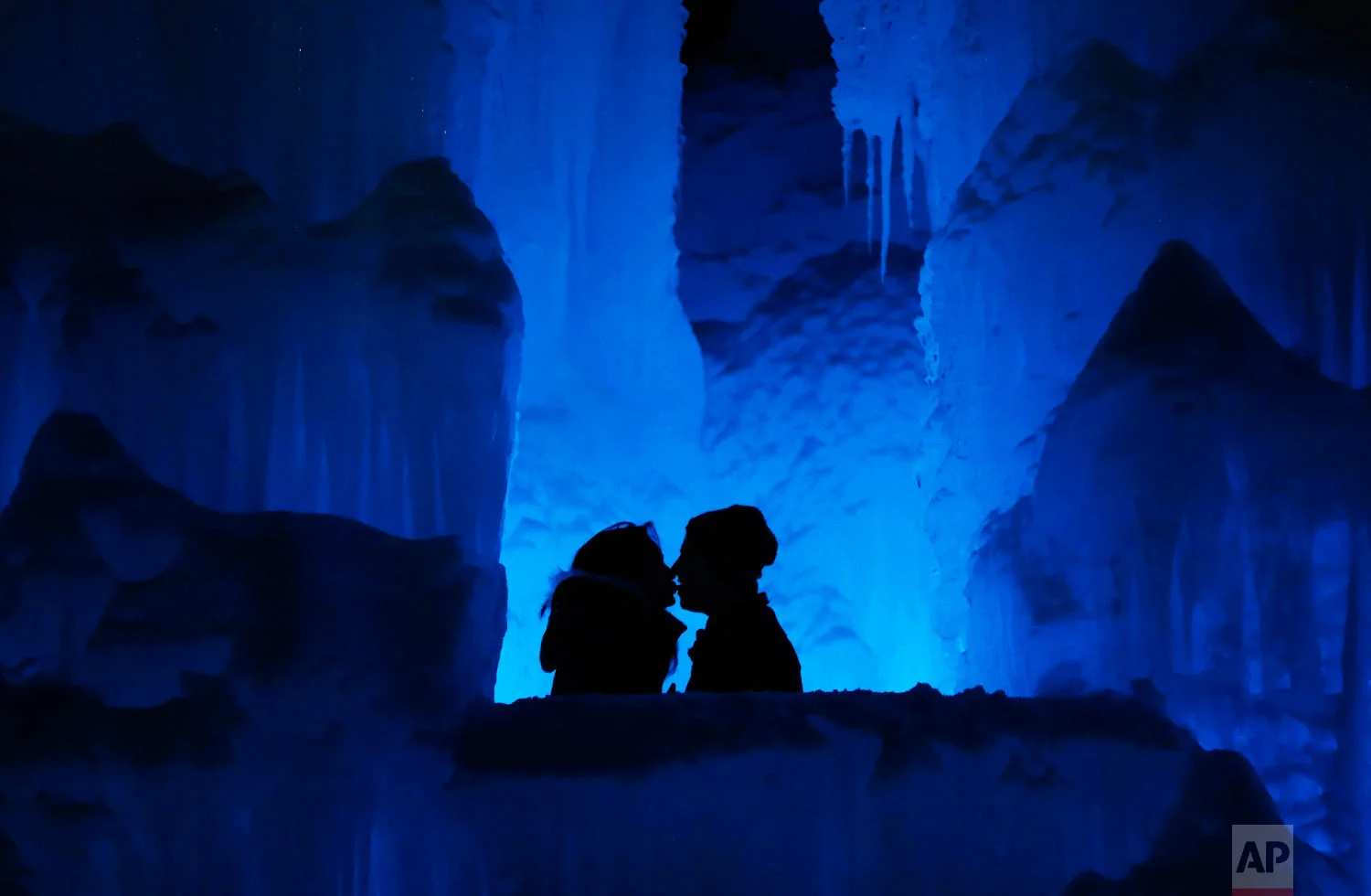 Romance heats up for a couple at Ice Castles in North Woodstock, N.H., on Jan. 25, 2019. "It's a really popular date night spot," said castle builder Matt Pasciuto. "I can’t tell you how many marriage proposals I’ve seen so far in the castle." (AP Photo/Robert F. Bukaty)