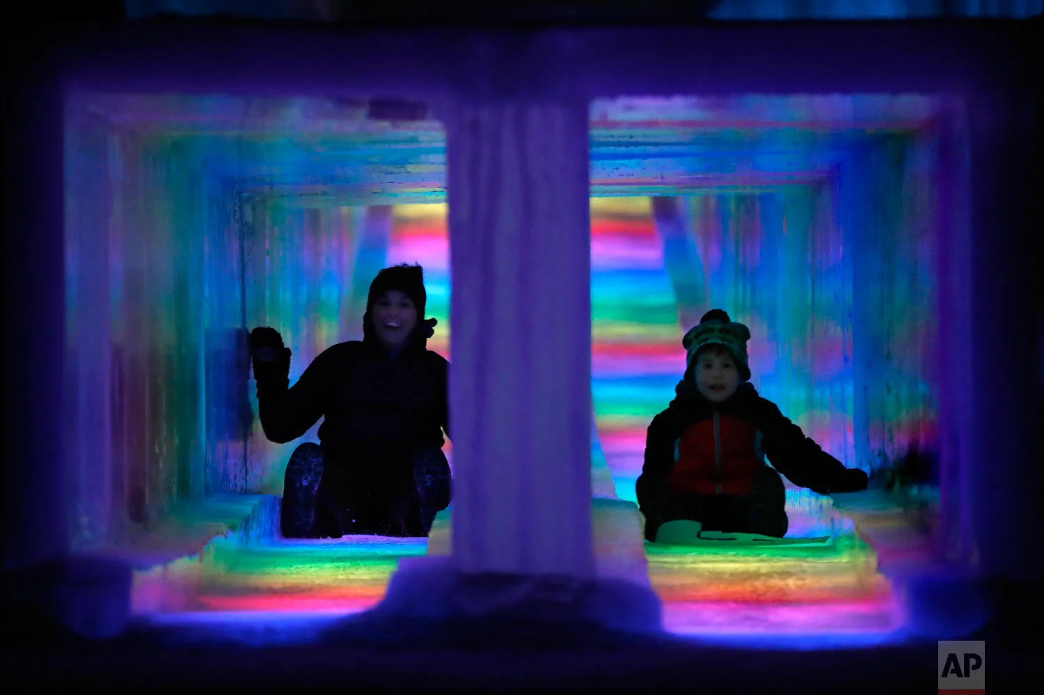 Visitors race down the side-by-side tunnels of a 97-foot ice slide at Ice Castles in North Woodstock, N.H., on Jan. 25, 2019. (AP Photo/Robert F. Bukaty)