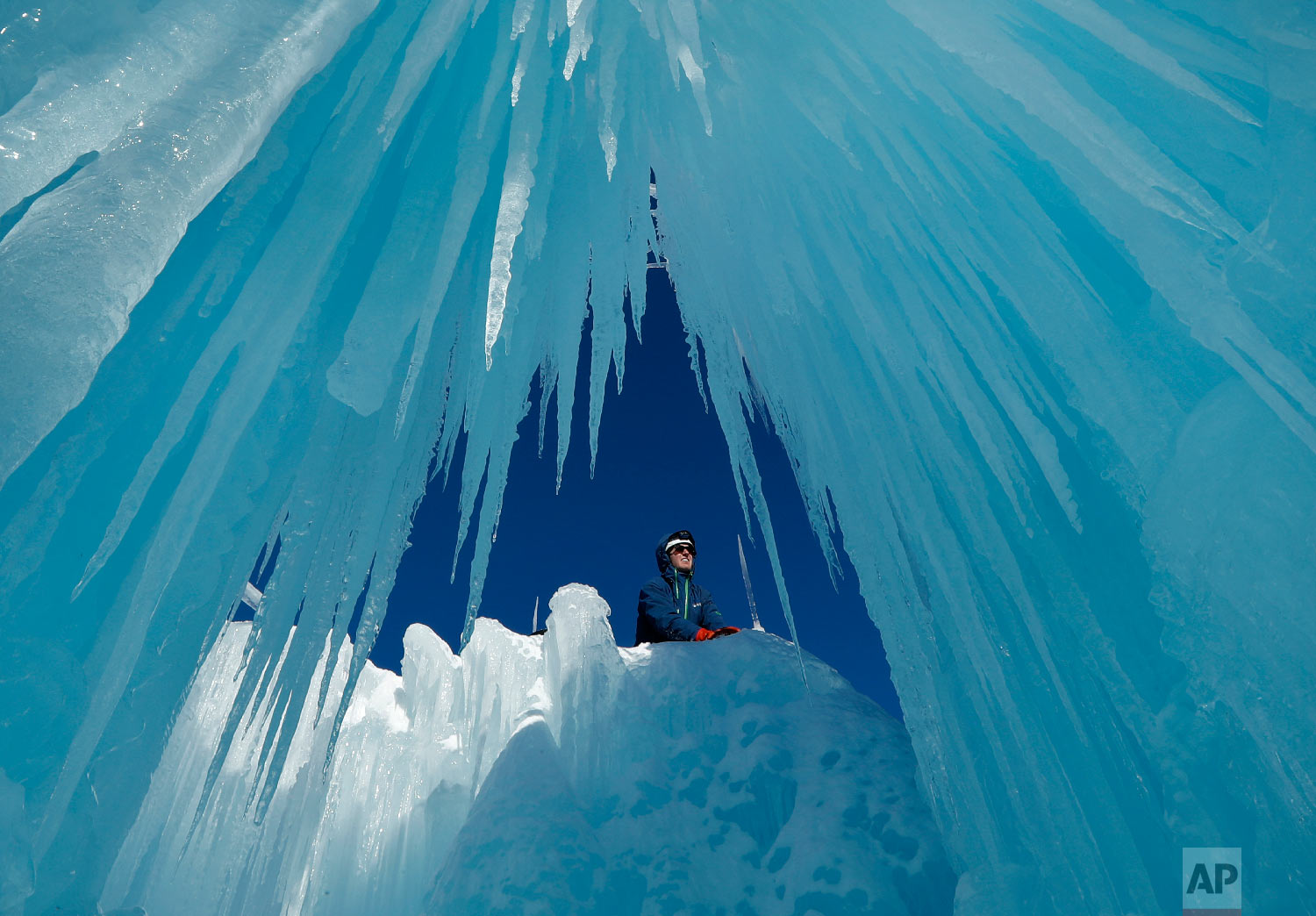 Matt Pasciuto places an icicle at the top of a wall at Ice castles in North Woodstock, N.H., on Jan. 28, 2019. (AP Photo/Robert F. Bukaty)