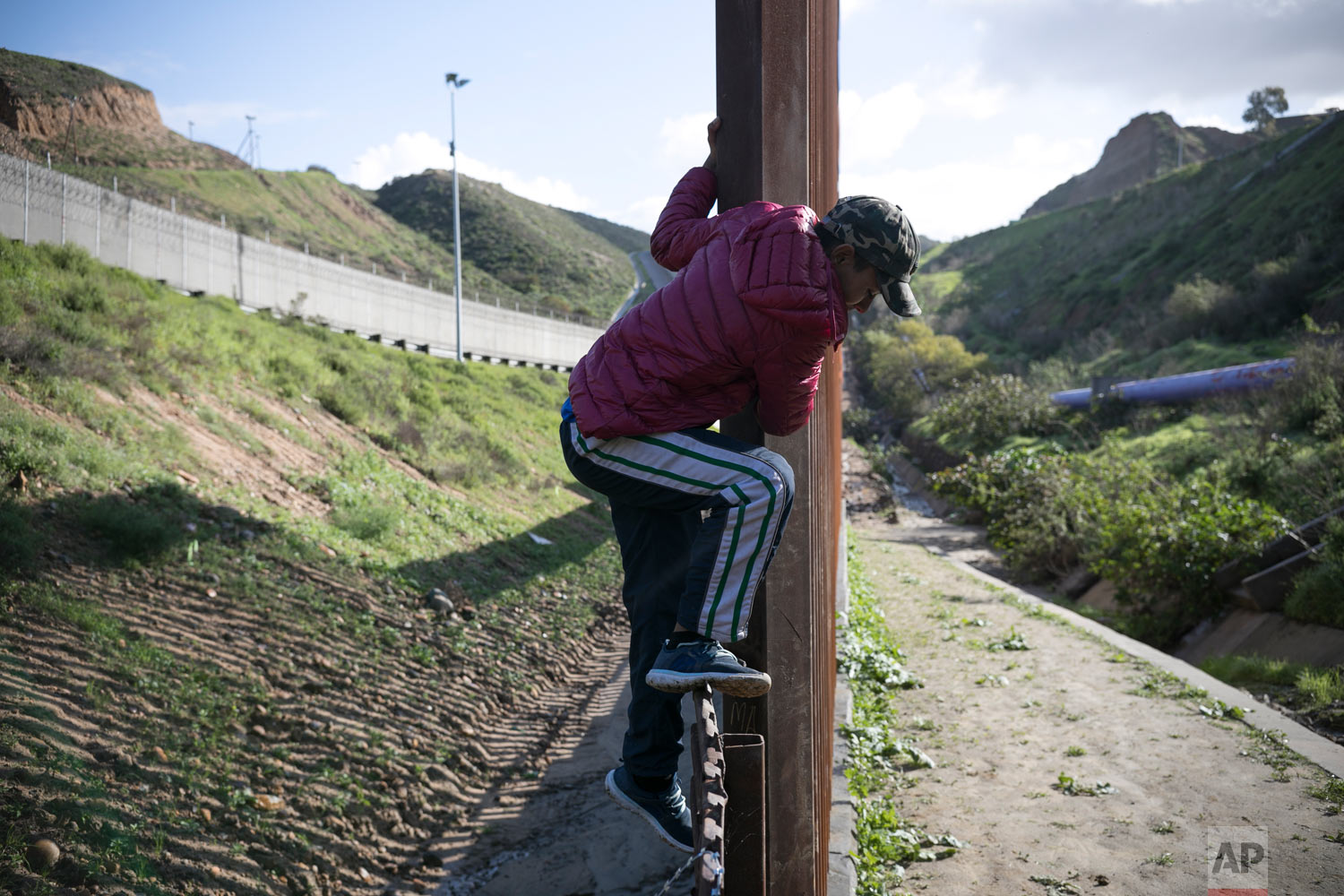  Teen Honduran migrant Josue Mejia Lucero climbs back over the U.S. border fence from San Diego to Tijuana, Mexico, after crossing it briefly to scout the area in an attempt to help his sister and her son reach the U.S. undetected from Tijuana, Mexic