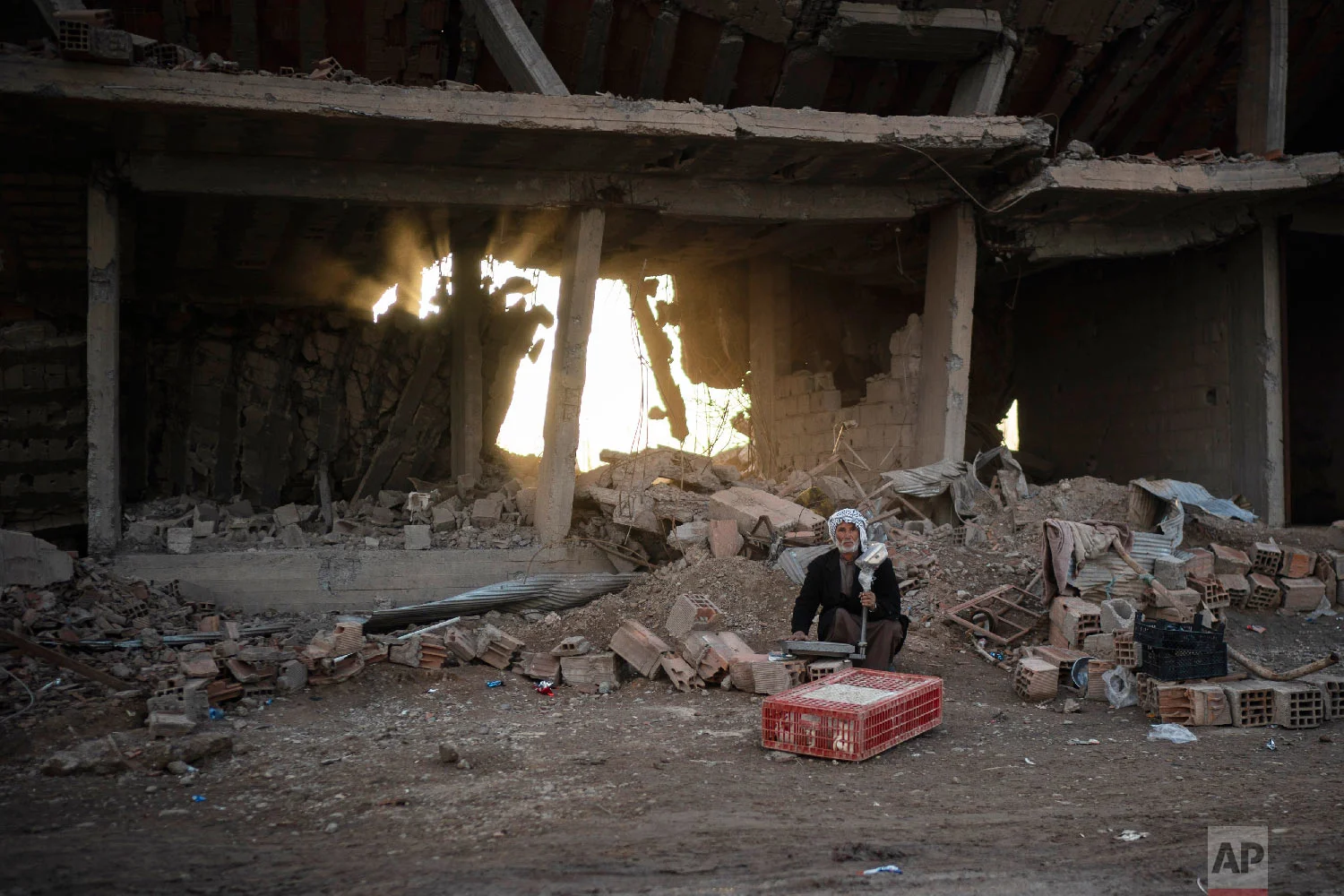  A man selling chicken sits in an area recently retaken by U.S.-backed Syrian Democratic Forces (SDF) from Islamic State militants in Hajin, Syria, Feb. 16, 2019. (AP Photo/Felipe Dana) 