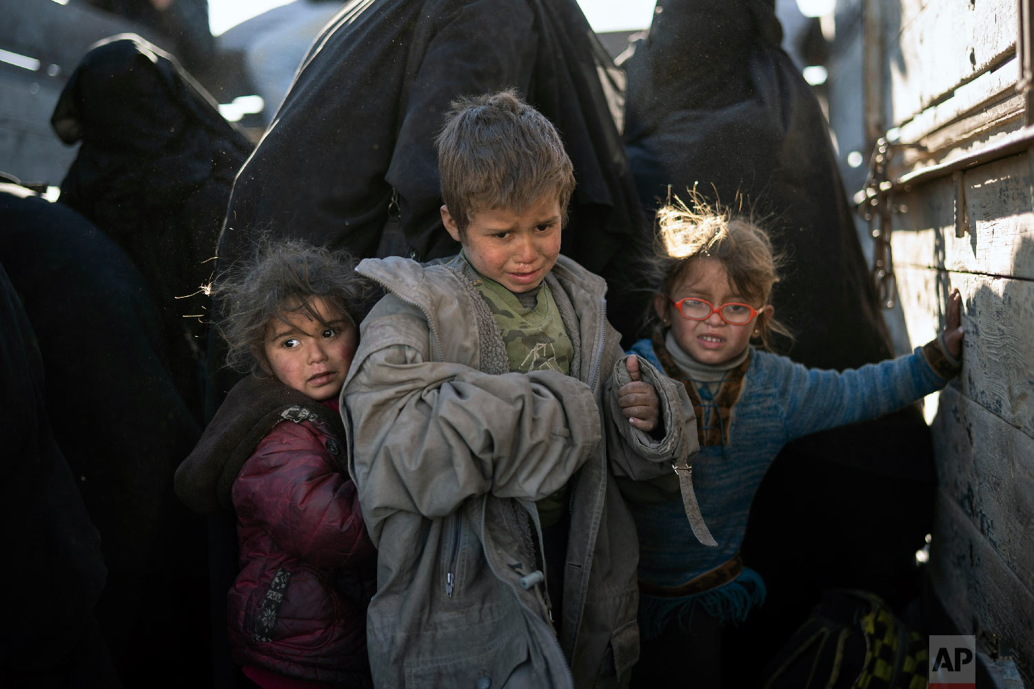 Women and children exit the back of a truck as they arrive at a U.S.-backed Syrian Democratic Forces (SDF) screening area after being evacuated out of the last territory held by Islamic State militants, in the desert outside Baghouz, Syria, Friday,