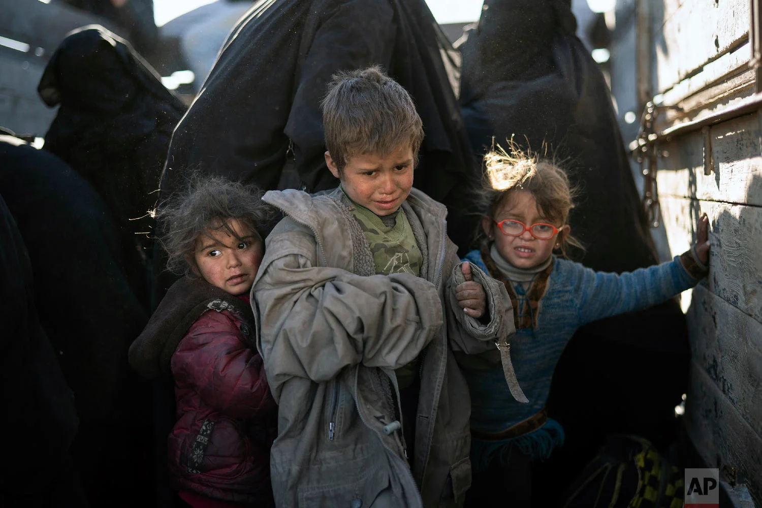 Women and children exit the back of a truck as they arrive at a U.S.-backed Syrian Democratic Forces (SDF) screening area after being evacuated out of the last territory held by Islamic State militants, in the desert outside Baghouz, Syria, Friday, March 1, 2019. (AP Photo/Felipe Dana)