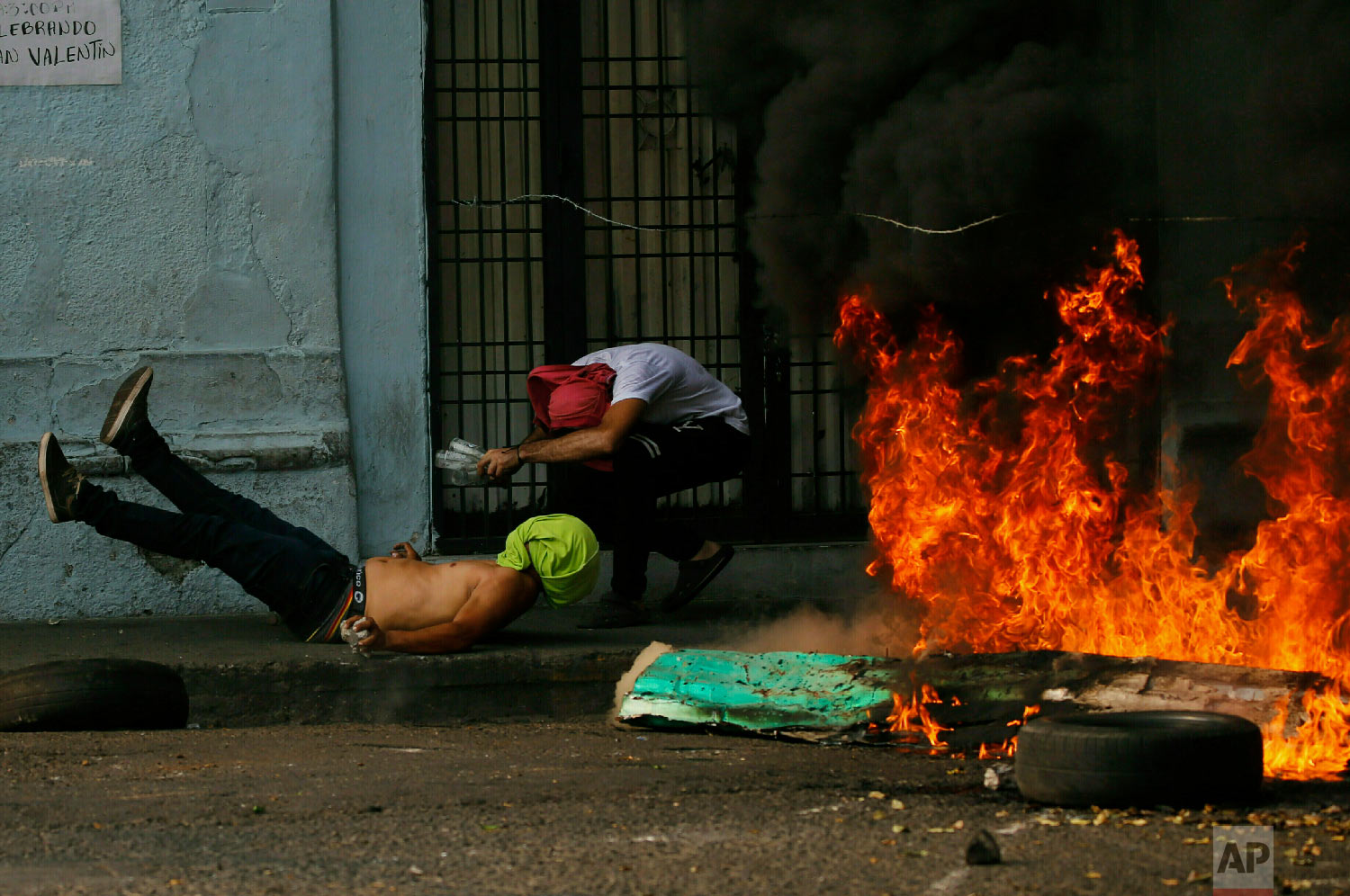 A demonstrator, left, falls after getting caught in a strand of barbed wire during clashes with the Bolivarian National Guard in Urena, Venezuela, near the border with Colombia, Saturday, Feb. 23, 2019. (AP Photo/Fernando Llano)