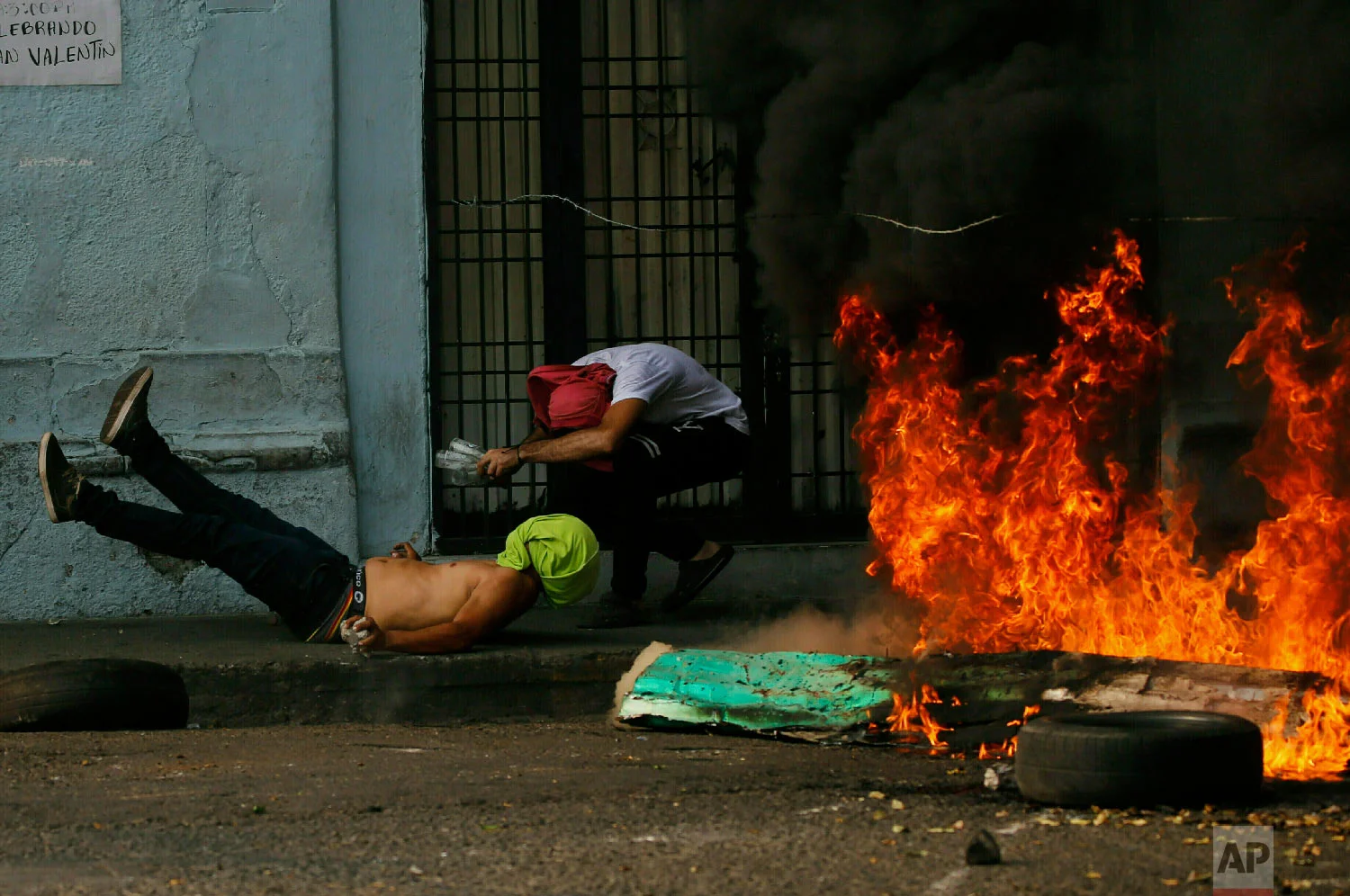 A demonstrator, left, falls after getting caught in a strand of barbed wire during clashes with the Bolivarian National Guard in Urena, Venezuela, near the border with Colombia, Saturday, Feb. 23, 2019. (AP Photo/Fernando Llano)