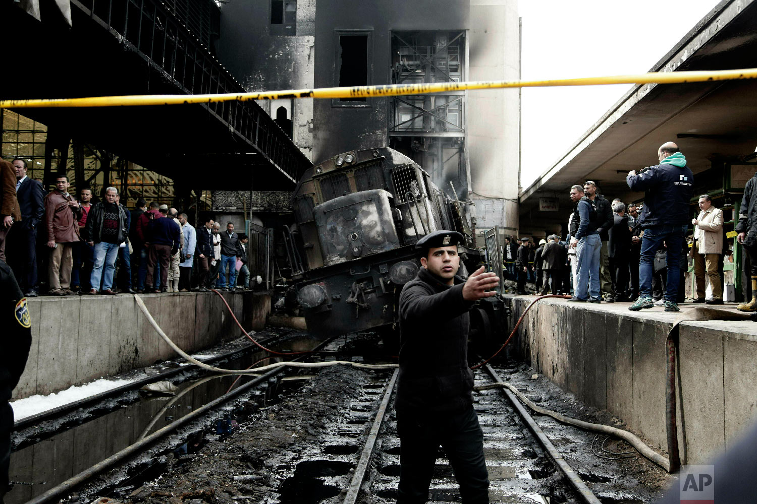 Policemen stand guard in front of a damaged train inside Ramsis train station in Cairo, Egypt, Wednesday, Feb. 27, 2019. (AP Photo/Nariman El-Mofty)