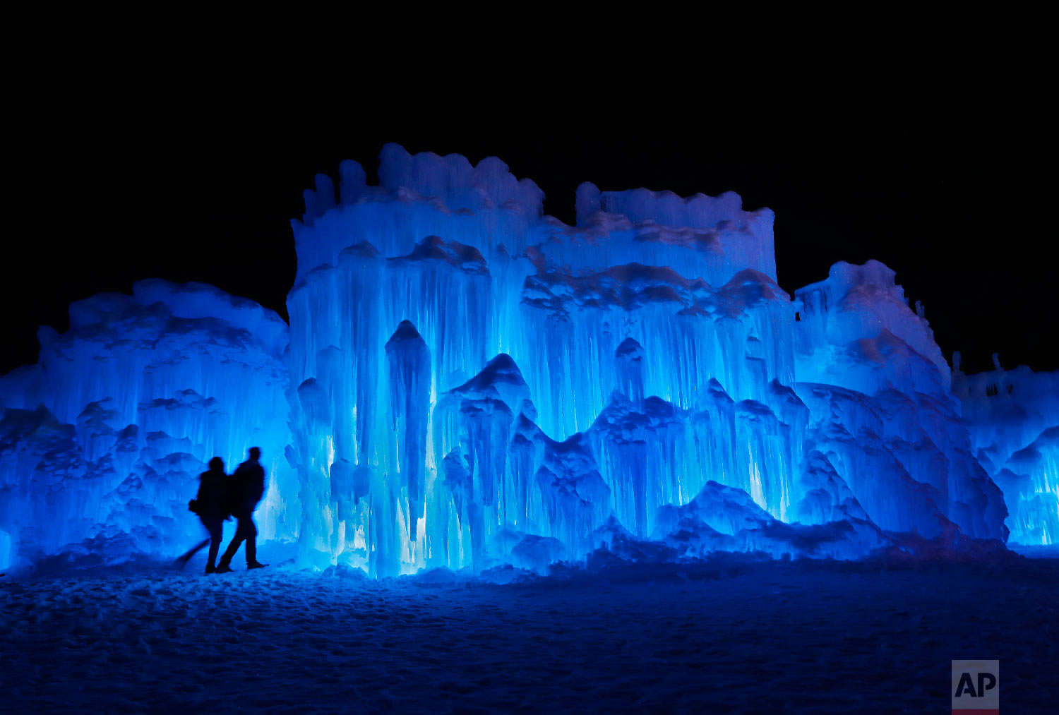 In this Saturday, Jan. 26, 2019, photo, a couple heads towards an entrance to a cavern at Ice Castles in North Woodstock, N.H. (AP Photo/Robert F. Bukaty)