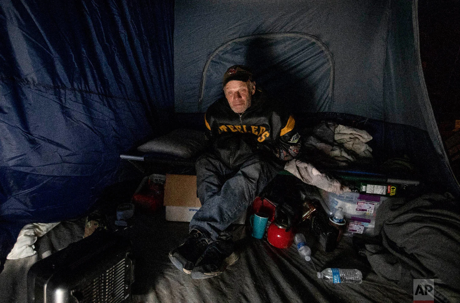James Huebner sits in his tent in the backyard of a home where he's living with his son and brother after becoming homeless from Hurricane Michael in Youngstown, Fla, Wednesday, Jan. 23, 2019. (AP Photo/David Goldman)