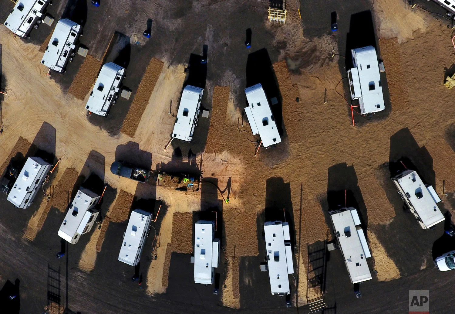 A worker sprays straw around newly setup Federal Emergency Management Agency trailers for residents left homeless by Hurricane Michael in Panama City, Fla, Thursday, Jan. 24, 2019. (AP Photo/David Goldman)