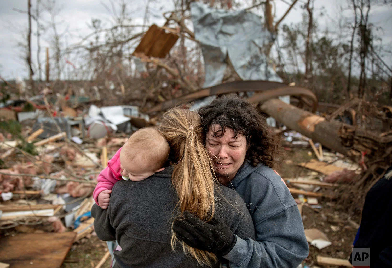 Carol Dean, right, cries while embraced by Megan Anderson and her 18-month-old daughter Madilyn, as Dean sifts through the debris of the home she shared with her husband, David Wayne Dean, who died when a tornado destroyed the house in Beauregard, Ala., March 4, 2019. "He was my wedding gift," said Dean of her husband whom she married three years ago. "He was one in a million. He'd send me flowers to work just to let me know he loved me. He'd send me some of the biggest strawberries in the world. I'm not going to be the same." (AP Photo/David Goldman)