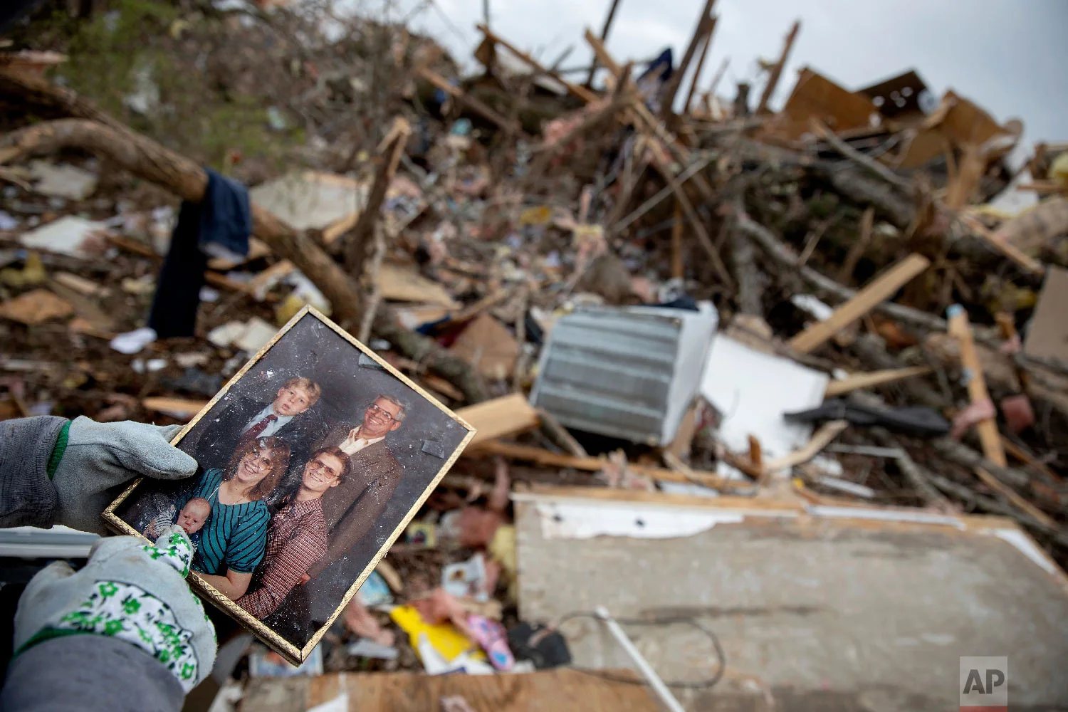 Danny Allen recovers a family photo while sifting through the debris of a friend's home destroyed in Beauregard, Ala., March 4, 2019. (AP Photo/David Goldman)