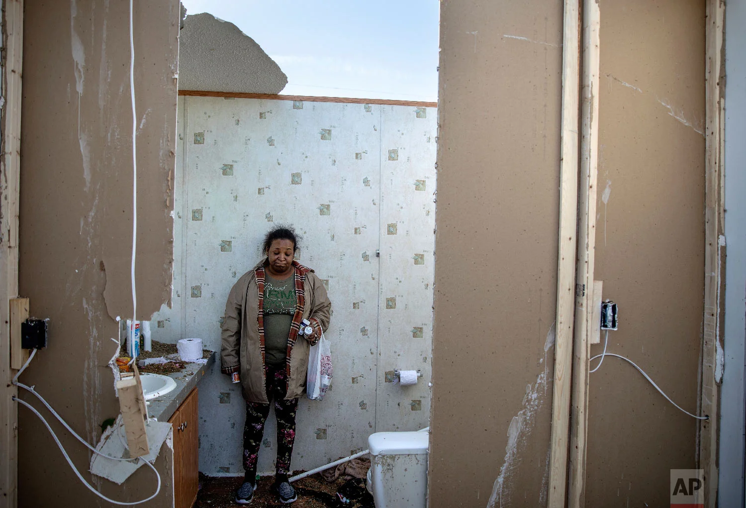 Shiraka Baker stands in the bathroom where she rode out a tornado with her husband and three children as she retrieves belongings from the damaged home in Beauregard, Ala., March 4, 2019. (AP Photo/David Goldman)