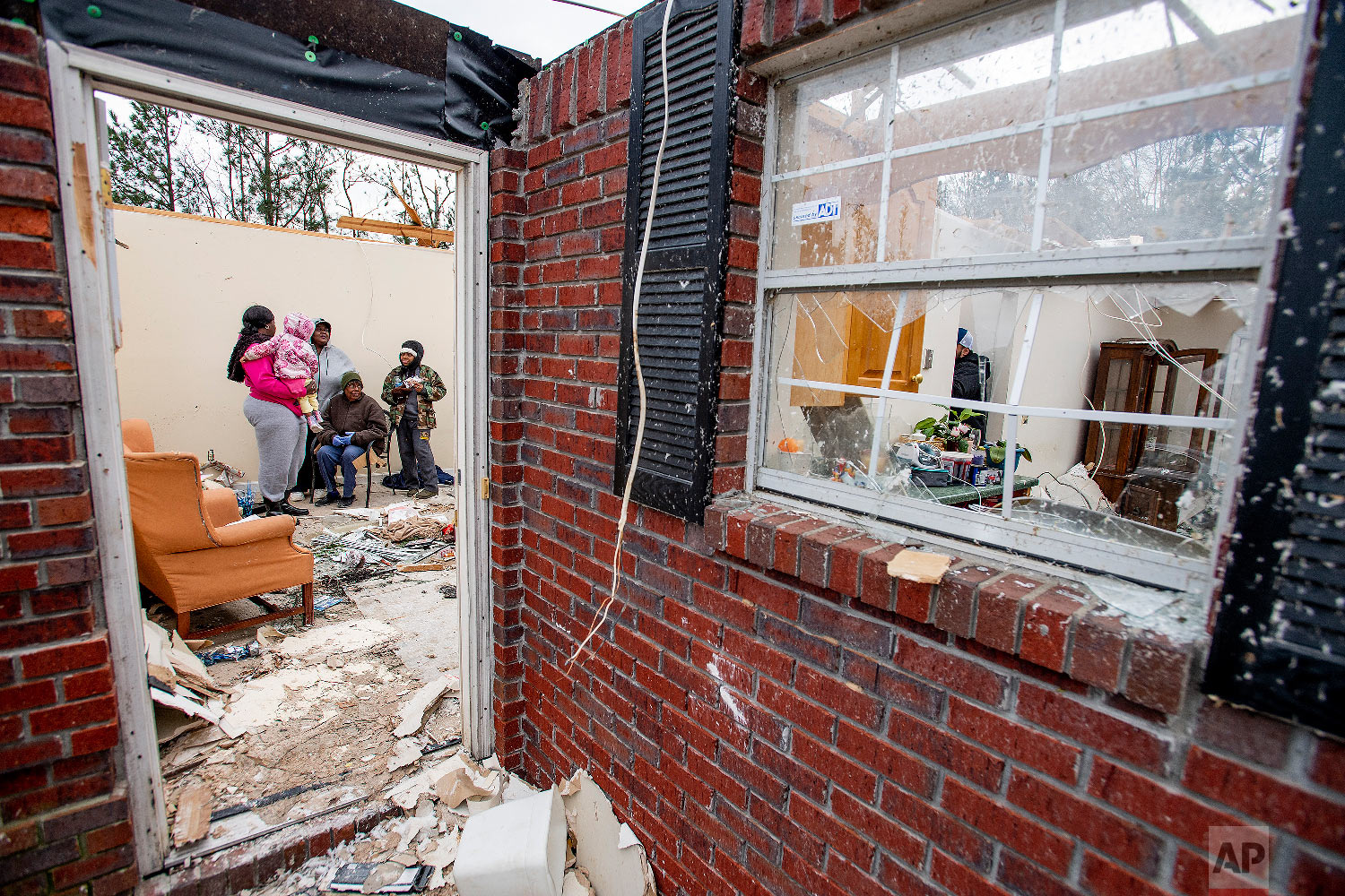 Dorothy Wilborn, seated, is comforted by her family in her home near Beauregard, Ala., on March 4, 2019, that lost it's roof in the fatal tornado that struck the area on Sunday afternoon. (Mickey Welsh/The Montgomery Advertiser via AP)